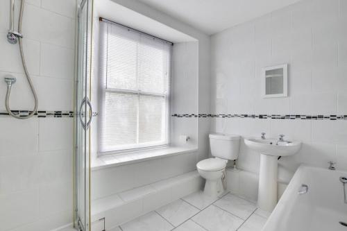 a white bathroom with a toilet and a sink at Mizpah in Mousehole