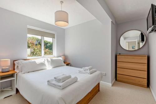 Un dormitorio con una gran cama blanca y un espejo. en Flat 9 Clifton Court, en Croyde