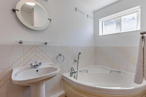 Un baño con lavabo, bañera y espejo. en Flat 9 Clifton Court, en Croyde