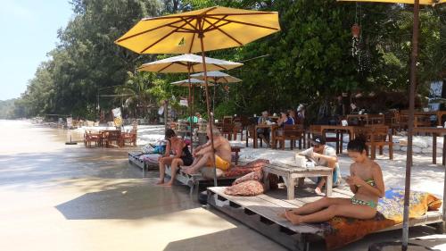 a group of people sitting on the beach under an umbrella at JJ Beach Resort & JJ Seafood in Ko Phayam