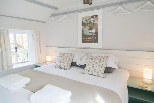 ein Schlafzimmer mit einem weißen Bett und zwei Kissen in der Unterkunft Molly Muppet in Mousehole