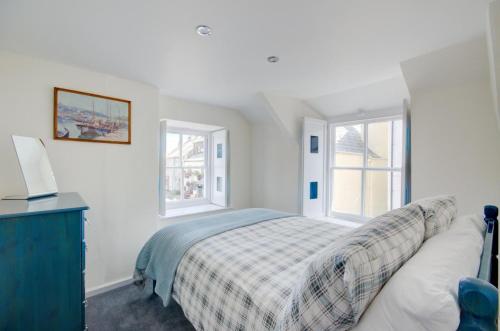 een witte slaapkamer met een bed en twee ramen bij 2 Bed in West Looe oc-l30054 in Looe