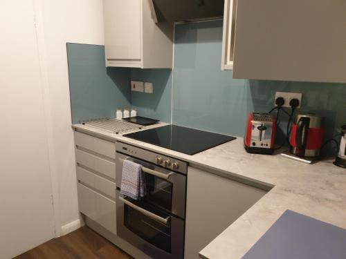 een keuken met een fornuis en een aanrechtblad bij Cosy Family Flat in Elswick
