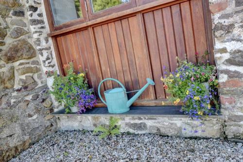 a window with a wooden door with flowers and a bucket at Cranscombe Barn in Countisbury