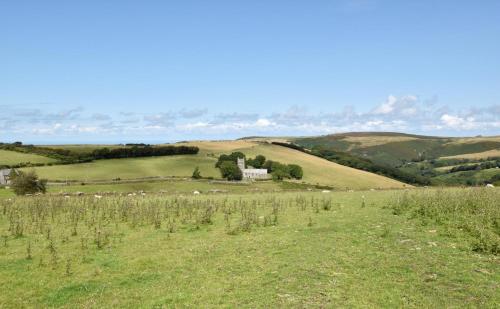 a field of green grass with a house in the distance at Cranscombe Barn in Countisbury