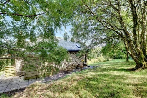 a stone building with a bench in a yard at Cranscombe Barn in Countisbury