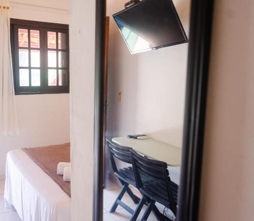 a mirror reflecting a room with a table and a bed at Pousada Pitaya Maresias in Maresias