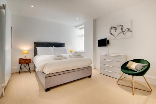 ein weißes Schlafzimmer mit einem Bett und einem Stuhl in der Unterkunft 3 Little Beach in Woolacombe