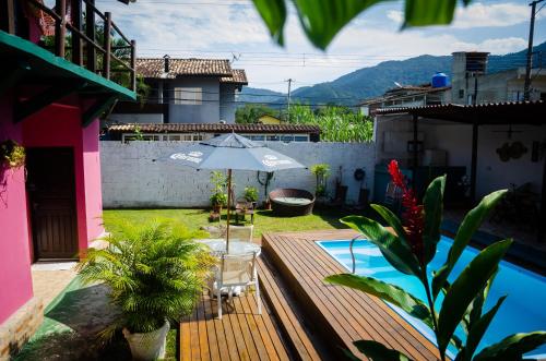 a patio with an umbrella and a swimming pool at Pousada Pitaya Maresias in Maresias