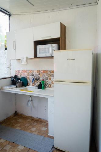 a kitchen with a white refrigerator and a sink at Pousada Pitaya Maresias in Maresias