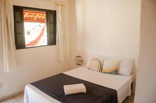 a white bedroom with a bed and a window at Pousada Pitaya Maresias in Maresias