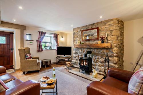 a living room with a stone fireplace and a tv at Broats Barn in Ingleton
