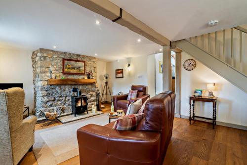 a living room with a couch and a stone fireplace at Broats Barn in Ingleton