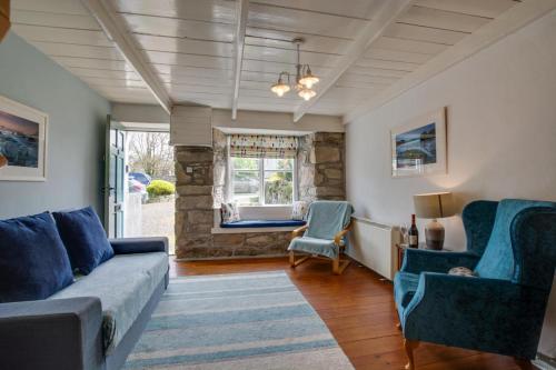 een woonkamer met een bank en stoelen en een raam bij Wills Cottage in Lower Boscaswell