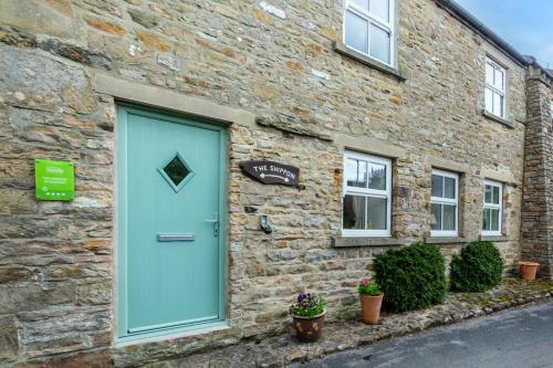 a blue door on the side of a brick building at The Shippon in Askrigg in Askrigg