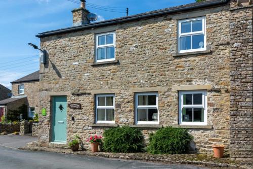an old stone house with a blue door and windows at The Shippon in Askrigg in Askrigg