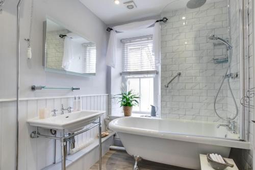 a white bathroom with a tub and a sink at Seahorse Cottage in Mousehole