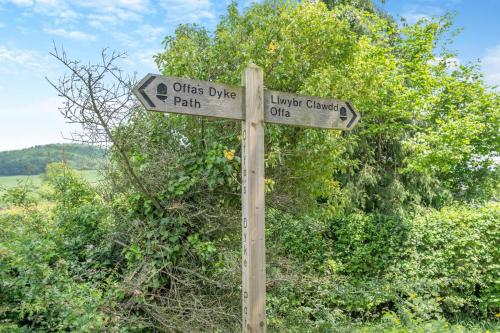 a wooden street sign with two signs on it at Little Hendre Barn in Wonastow