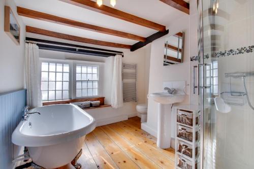 a bathroom with a white tub and a sink at Rooks Cottage in Askrigg
