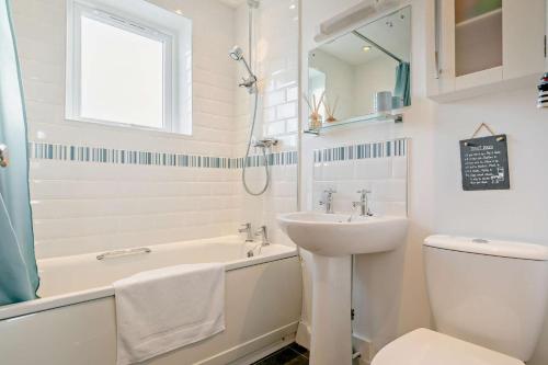 a white bathroom with a sink and a tub and a toilet at Oceans Nest - Carbis Bay in Carbis Bay