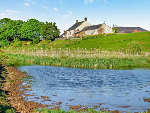 a house on top of a hill next to a pond at Vallum at Hadrians Wall in Irthington