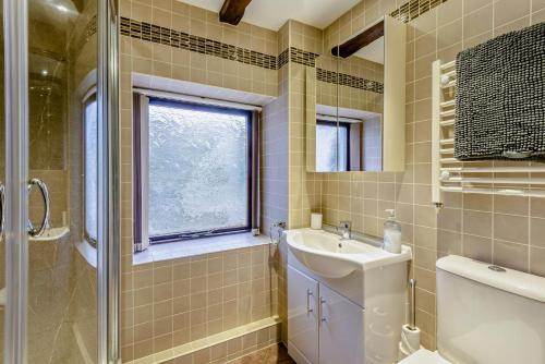 a bathroom with a sink and a toilet and a window at Rosie Cottage in Bassenthwaite