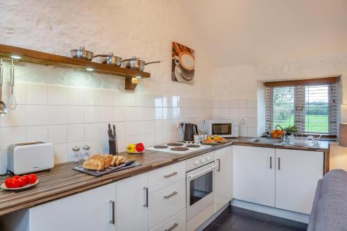 a kitchen with white cabinets and a wooden counter top at Bodlondeb in Abererch