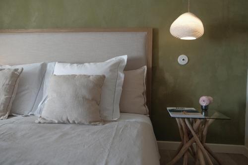 a bed with white pillows and a side table with a lamp at Les Jardins de Sitaara in Cucuron