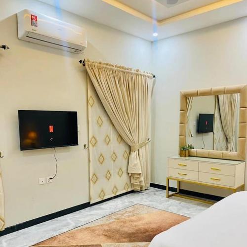 a bedroom with a television and a dresser with a mirror at Majestic Family Lodges in Islamabad
