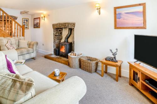 a living room with a fireplace and a tv at Llety-Cariad in Trecastle