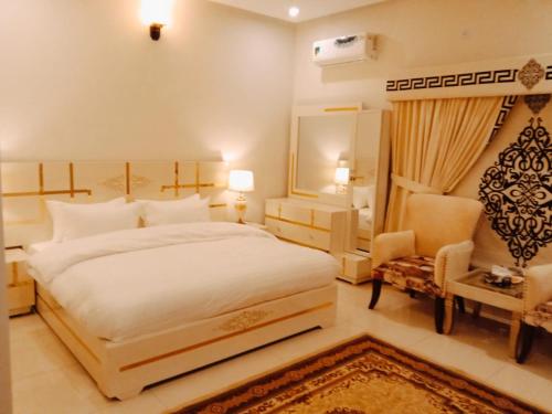 a bedroom with a large white bed and a chair at Majestic Family Lodges in Islamabad