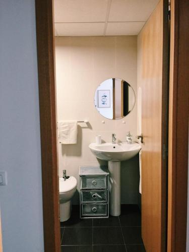 a bathroom with a sink and a toilet and a mirror at Hogar Cómodo y cerca de playa in Oliva