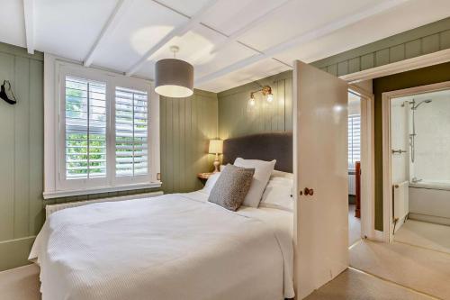 a bedroom with a large white bed and windows at Trehawn Cottage in Saint Columb Major