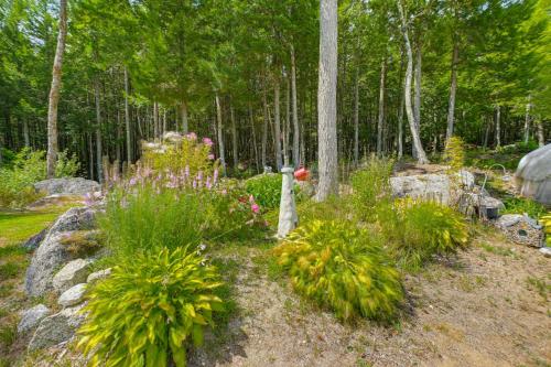 a garden with flowers and rocks and trees at Explore Coastal Maine! Cozy Apt with Yard and Garden in Orland