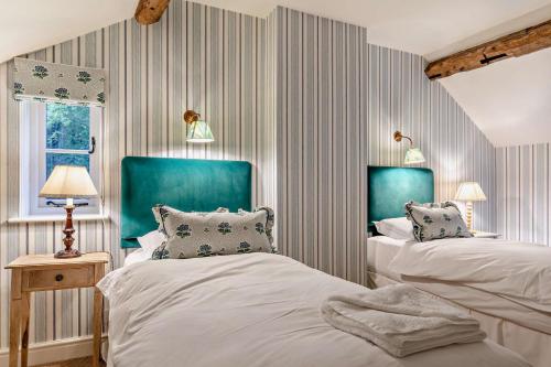 two beds in a bedroom with blue and white stripes at Hall Cottage in Eccleshall