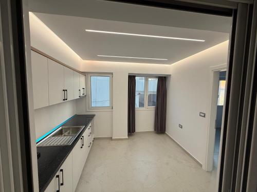 une cuisine avec des armoires blanches et des comptoirs noirs dans l'établissement Dashaj Rooms 301, à Ksamil