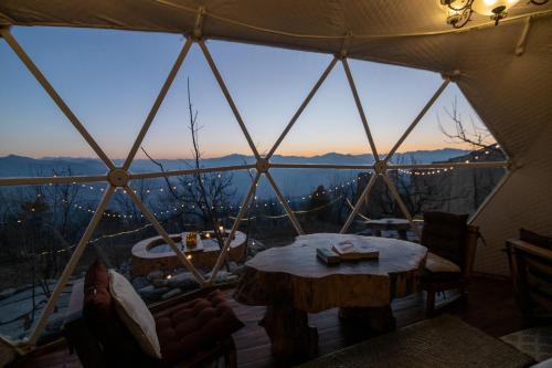 a tent with a table and a view of the mountains at Glamoreo - The Walnut Glamp in Cheog