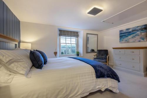 a bedroom with a large white bed and a dresser at River Watch - Fowey in Fowey