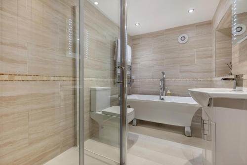 a bathroom with a tub and a toilet and a sink at River Watch - Fowey in Fowey