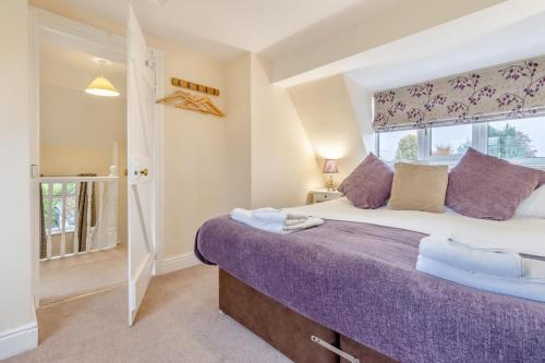 una camera da letto con un grande letto con lenzuola viola e una finestra di Orchard Cottage a Preesgreen