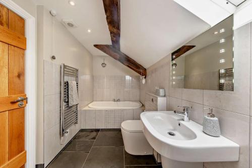 a bathroom with a sink and a toilet and a tub at Parlwr Mawr in Dyffryn