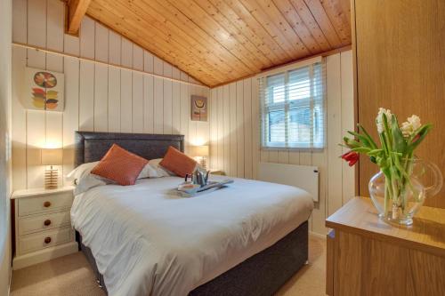 ein Schlafzimmer mit einem großen Bett und einer Vase aus Blumen in der Unterkunft Birch Lodge in Thornton Watlass