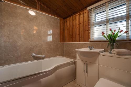 ein Badezimmer mit Badewanne, Toilette und Waschbecken in der Unterkunft Birch Lodge in Thornton Watlass
