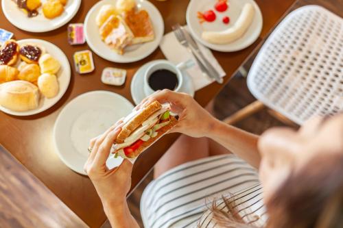 a woman sitting at a table eating a sandwich at ibis Styles Rondonopolis in Rondonópolis