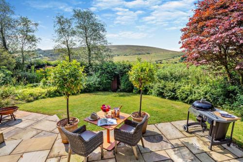 a patio with a table and chairs and a grill at The Secret Garden - Withypool in Withypool