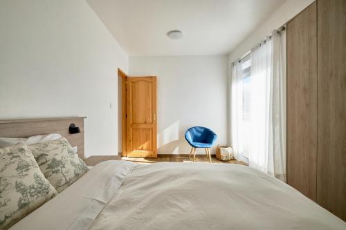 a bedroom with a bed with a blue chair next to a window at Maimara Hotel in Huaraz