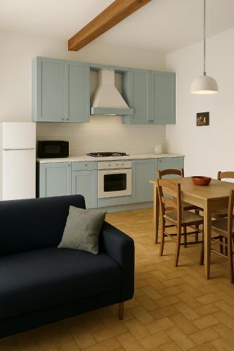 a kitchen with blue cabinets and a table with a couch at Volta Como Lake apartament in Brunate