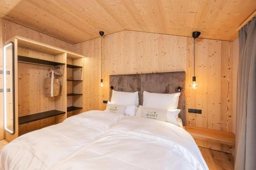 a large white bed in a room with wooden walls at Munt Dolomiti Farm in Plancios
