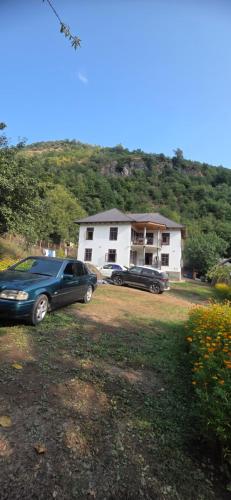two cars parked in a yard in front of a house at Sim Guesthouse in Sım