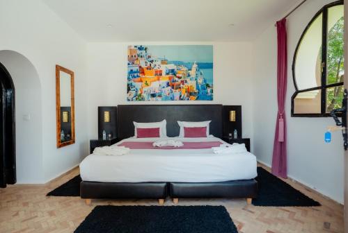 a bedroom with a large bed with a painting on the wall at DOMAINE DU DOUAR in Marrakech